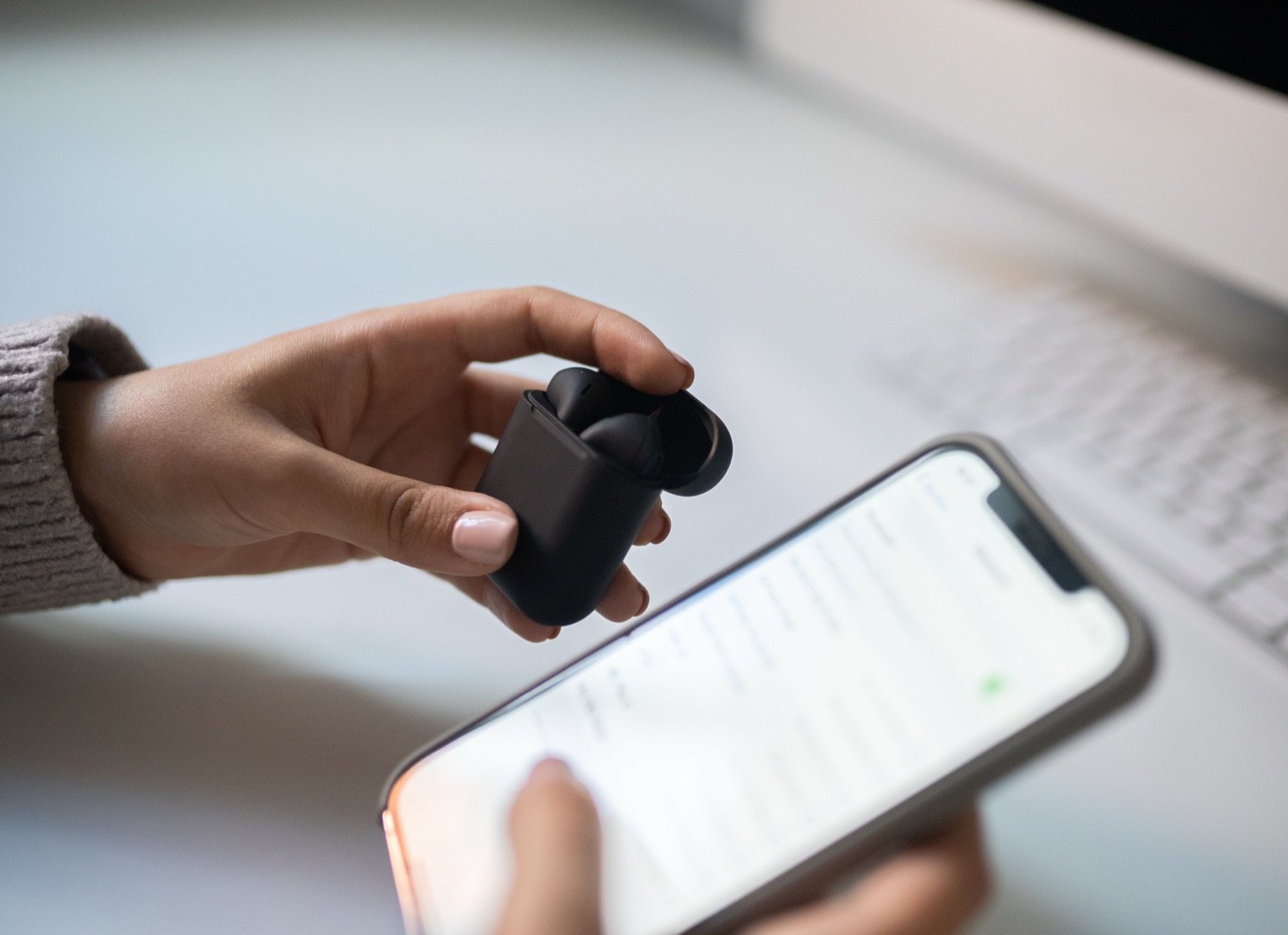 Hands holding earbuds and a phone
